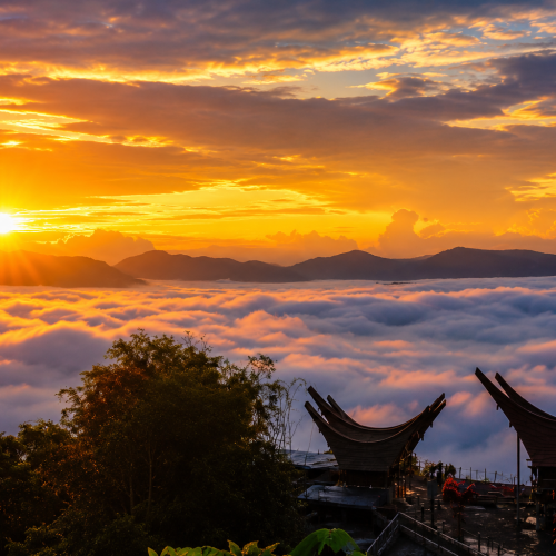 A breathtaking sunrise over the famous Sea of Clouds in Lolai, Toraja Highlands, with traditional Tongkonan houses overlooking a blanket of clouds in South Sulawesi, Indonesia.