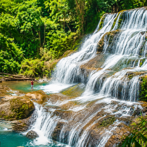 Crystal-clear Saliu Waterfall surrounded by lush tropical rainforest in South Sulawesi, Indonesia, featuring emerald pools, cascading waterfalls, and pristine jungle scenery.